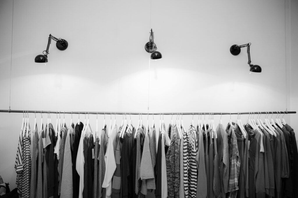 Une pièce remplie de vêtements. Il y a trois lampes qui éclairent les vêtements. L'image est en noir et blanc.