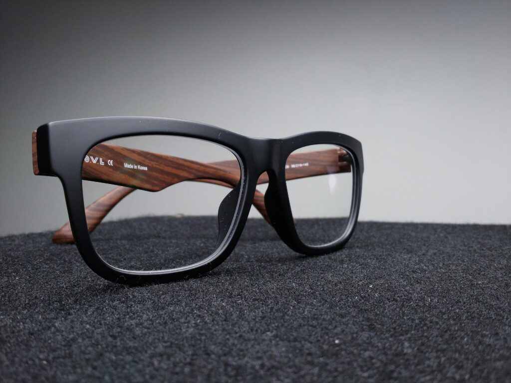 Une paire de lunettes sur une surface foncée, qui ressemble à un tapis.